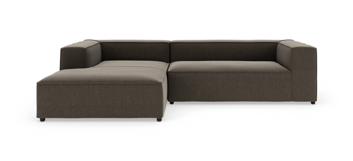 Modulsofa i L-form med venstre chaiselong i mørkebrun tekstil, lav kantet design på hvid baggrund.