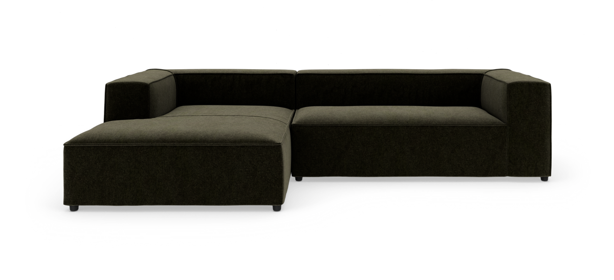 Modulsofa i mørkegrønt stof med venstrevendt chaiselong, kubisk design på hvid baggrund.