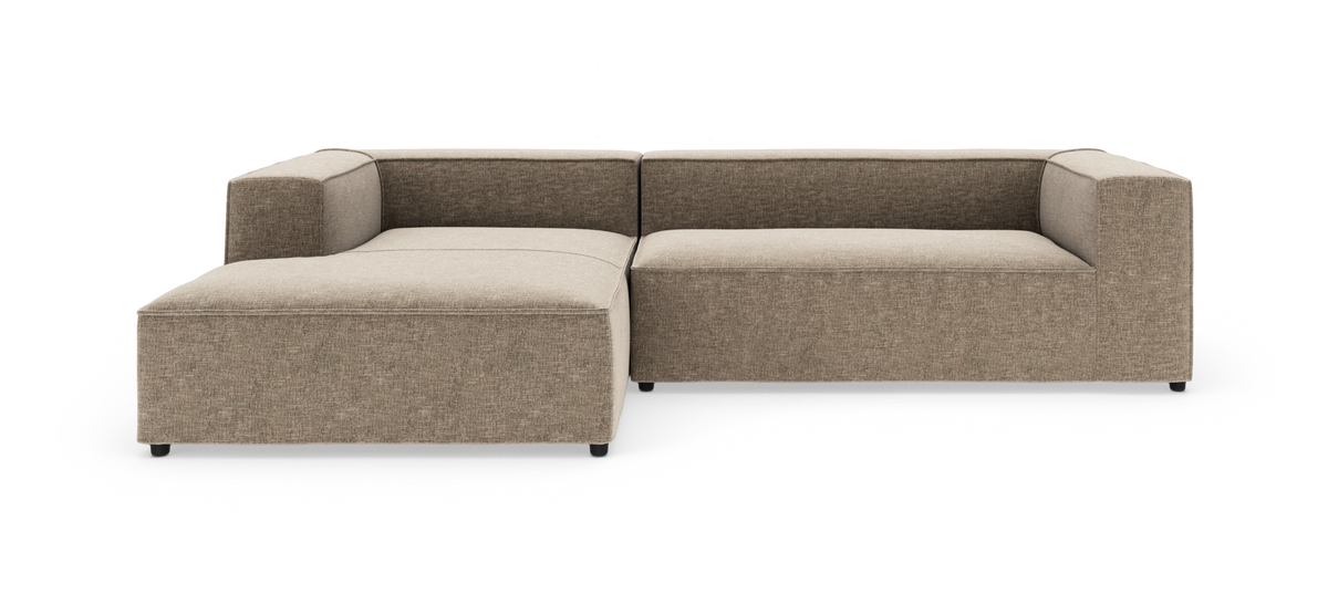 Beige modulsofa i L‑form med bred chaiselong til venstre, fritstående på hvid baggrund.