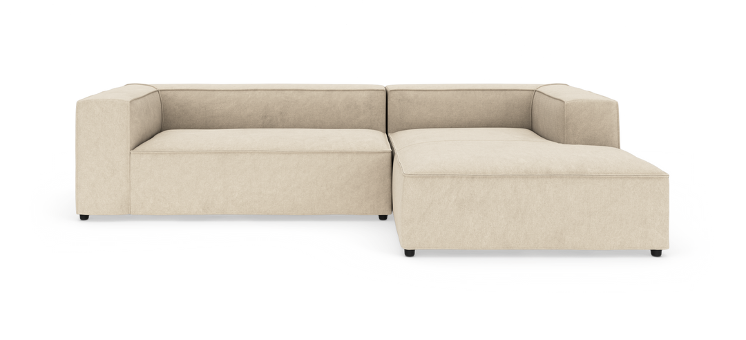 Beige modulsofa i L-form med bred chaiselong til højre.