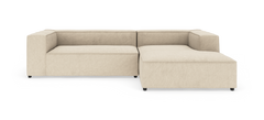 Beige modulsofa i L-form med bred chaiselong til højre.