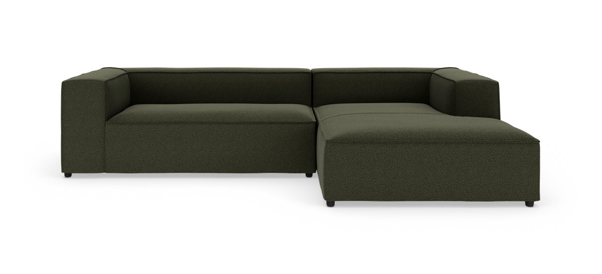 Mørkegrøn L-formet modulsofa i studiemiljø på hvid baggrund.
