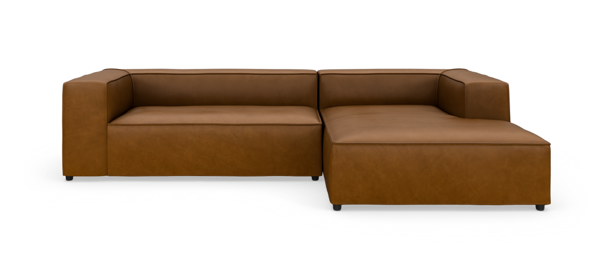 Brun læderhjørnesofa med chaiselong til højre på hvid baggrund.