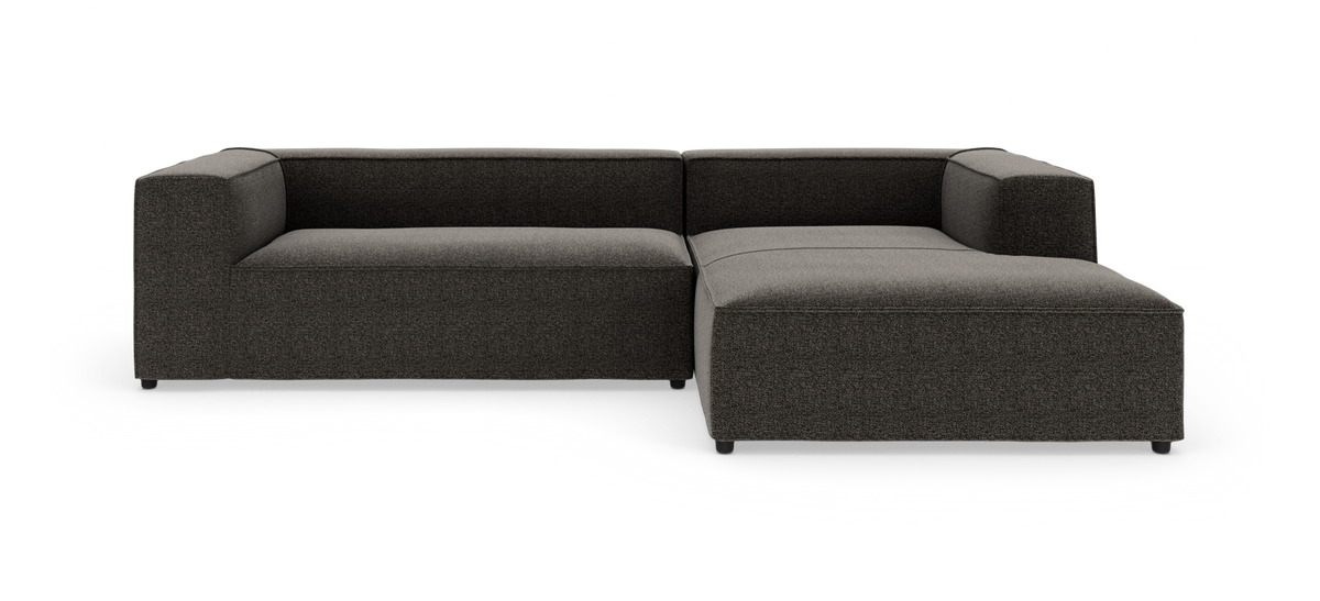 Mørkegrå L‑formet modulsofa med chaiselong til højre, fotograferet forfra i studie.