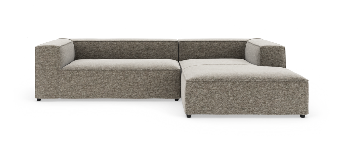 Modulær hjørnesofa med chaiselong til højre i grå-beige stof på hvid studiobaggrund.