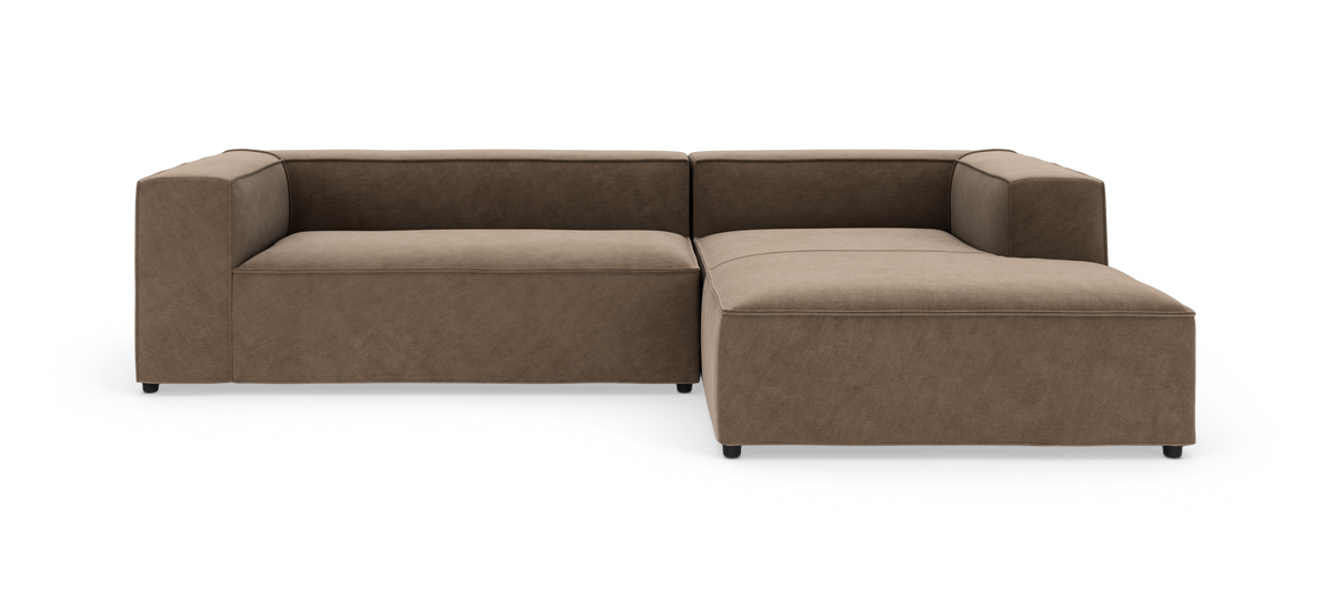 Brun L-formet modulsofa med bred chaiselong, lav ryg og kantede armlæn på hvid studiobaggrund.
