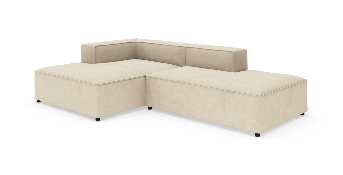 Modulær hjørnesofa i beige stof på hvid baggrund, med lav ryg og brede sædehynder.