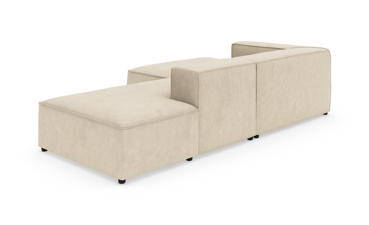 Beige modulsofa med chaiselong i L‑form, vist bagfra i vinkel på hvid baggrund.