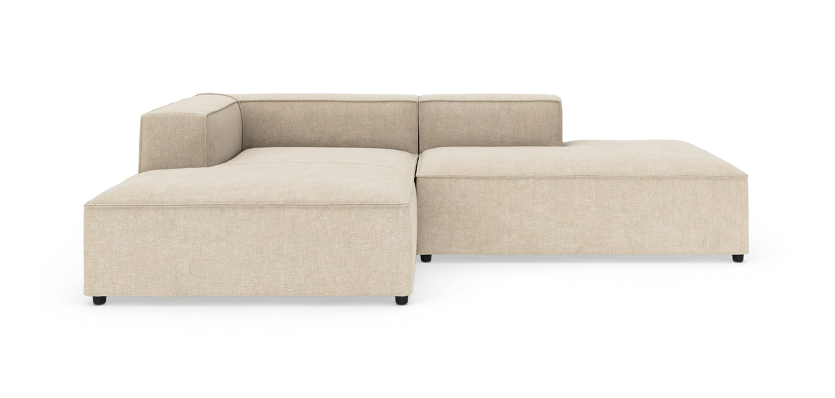Beige modulsofa i L-form med lav ryg og bløde linjer på hvid baggrund.