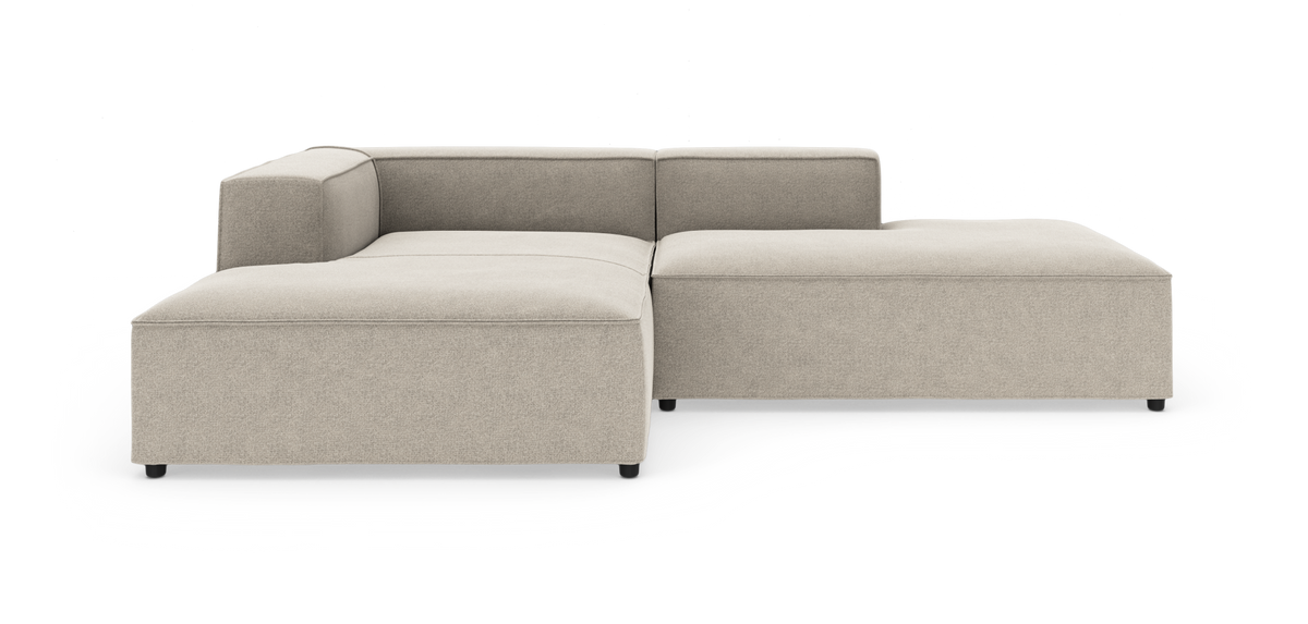Beige modulsofa i L‑form med lav ryg og bred chaiselong.