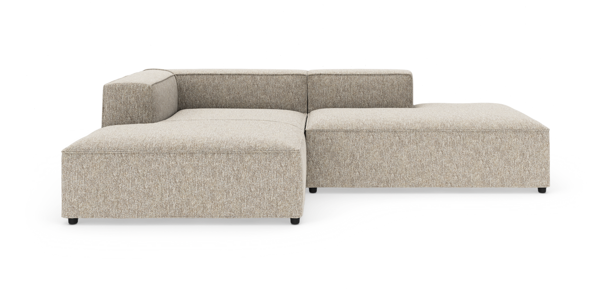 Beige modulsofa i L-form med lav ryg og brede sædehynder, fritlagt på hvid baggrund.
