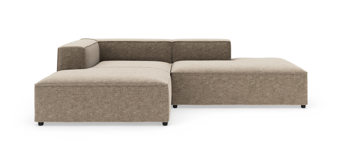 Modulær hjørnesofa i beige stof med chaiselong til højre, lav ryg og brede sæder, frilagt på hvid baggrund.