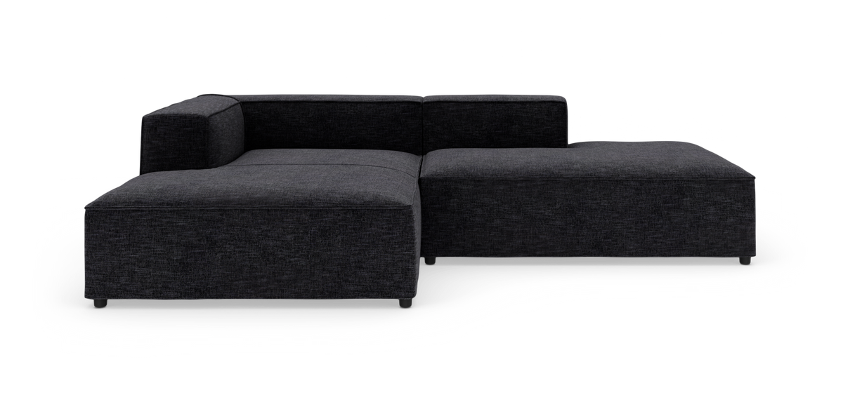 Mørkegrå modulsofa i L‑form på hvid baggrund.