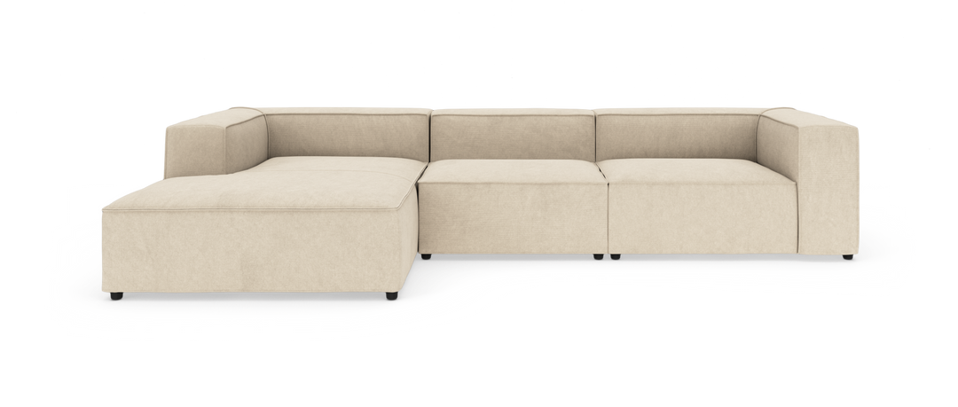 Beige modulsofa med chaiselong, lav profil og kubiske armlæn på hvid baggrund.