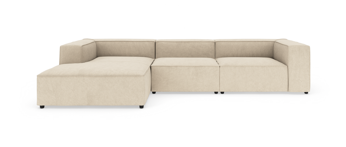 Beige modulsofa med chaiselong, lav profil og kubiske armlæn på hvid baggrund.