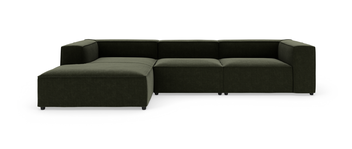 Mørkegrøn modulsofa med venstrevendt chaiselong i L‑form, fotograferet lige forfra mod hvid studiobaggrund.