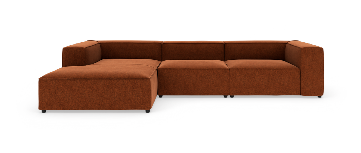 Modulær hjørnesofa i rustorange stof med venstrevendt chaiselong, fotograferet frontalt på hvid studiebaggrund.