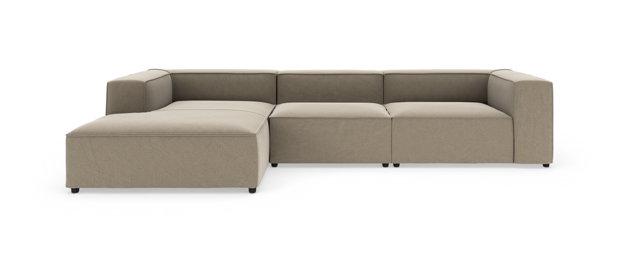 Modulær beige stofhjørnesofa med venstrevendt chaiselong, lav ryg og kubiske armlæn, frilagt på hvid baggrund.
