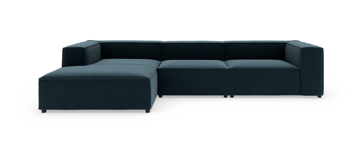 Modulsofa i mørk petrolblåt stof med venstrevendt chaiselong, frilagt på hvid baggrund.