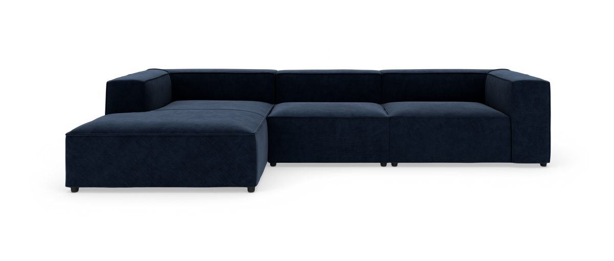 Mørkeblå modulsofa med venstrevendt chaiselong, fotograferet lige forfra på hvid baggrund.