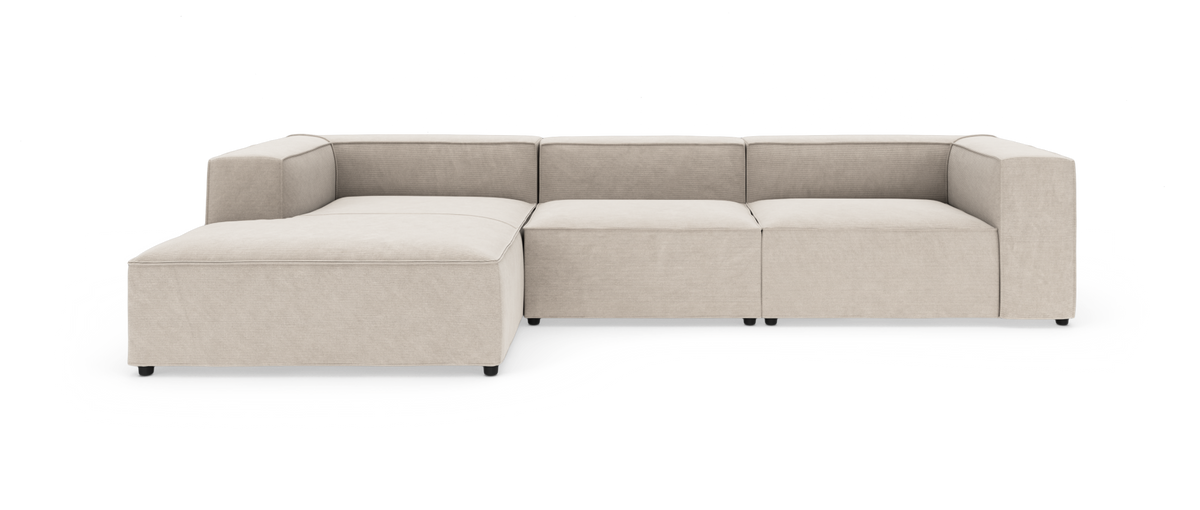Beige modulsofa med bred chaiselong til venstre, moderne kubisk design på hvid studiobaggrund.