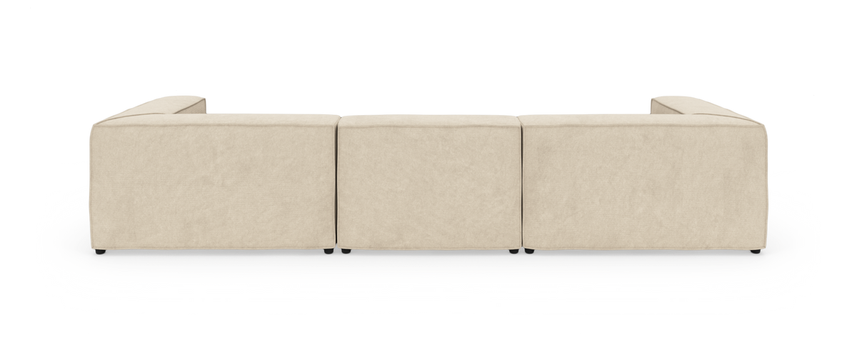 Beige modulsofa i L-form set bagfra, tre sædemoduler med åbne armlæn på begge sider.