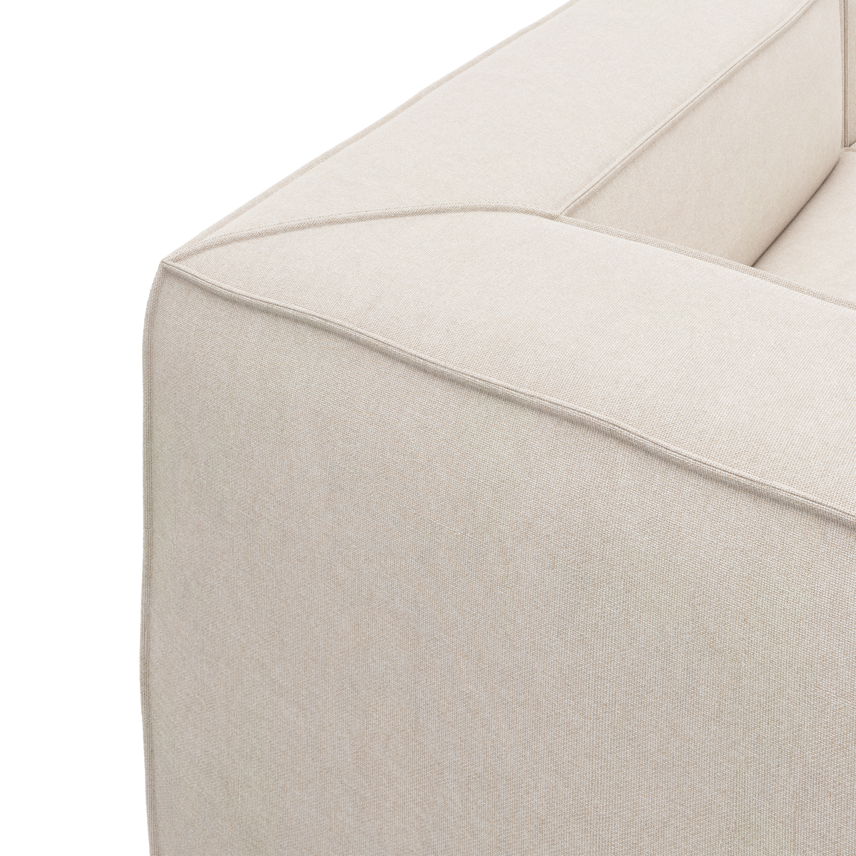 Nærbillede af beige stofsofa med bred armlæn og kantsyning, frilagt på hvid baggrund.