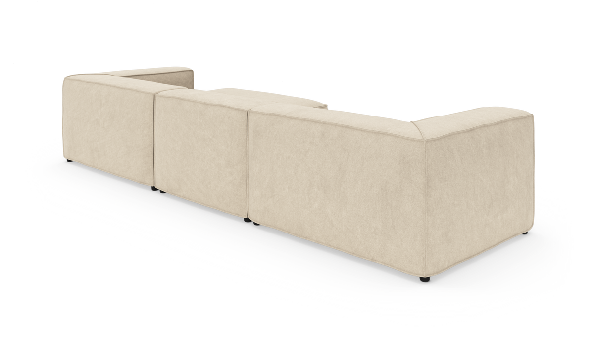 Modulær beige hjørnesofa set bagfra i studie, med bløde kubiske moduler.