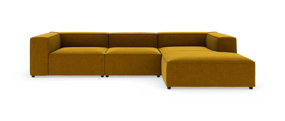 Modulsofa i L‑form i sennepsgul stof, frontvisning mod hvid baggrund.
