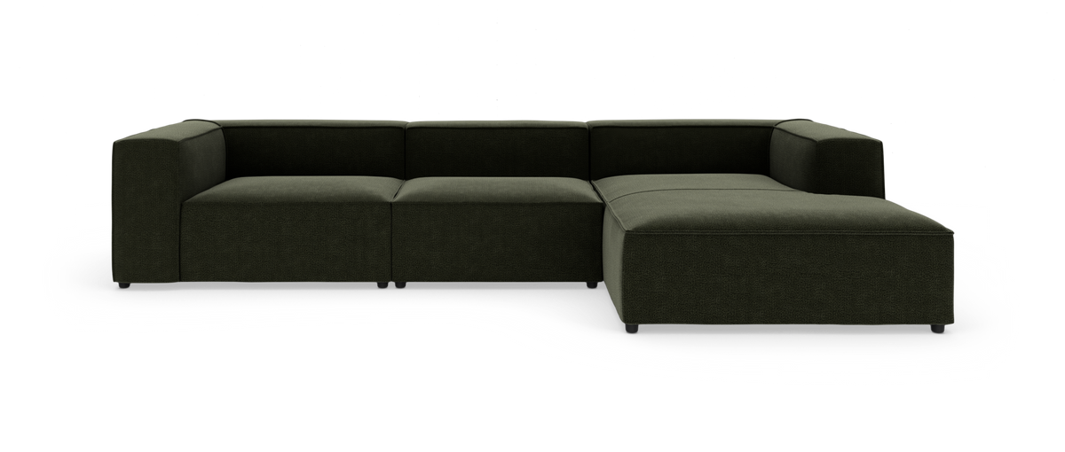 Modulsofa i mørkegrønt stof, L-form med højre chaiselong og lave blok-armlæn, fritstående mod hvid baggrund.