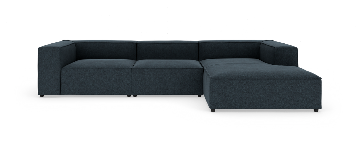 Modulær hjørnesofa i mørkeblåt stof med chaiselong til højre, frilagt på hvid baggrund.