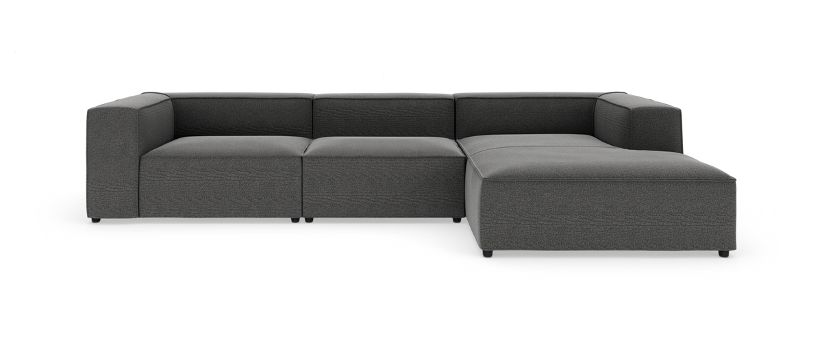 Mørkegrå modulsofa med chaiselong til højre, fotograferet lige forfra på hvid baggrund.