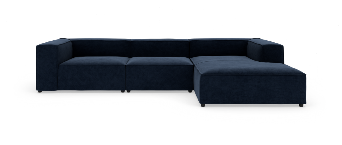 Mørkeblå modulsofa i hjørnekonfiguration med chaiselong til højre, frontvinkel mod hvid baggrund.