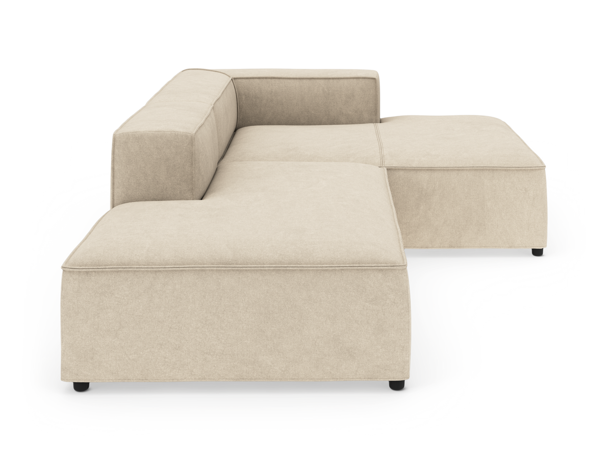 Beige modulopbygget L-sofa med lav ryg og bred chaiselong, fritlagt på hvid baggrund.