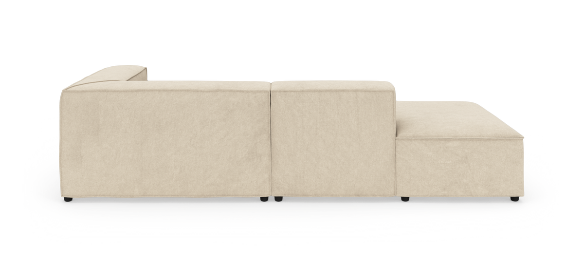 Beige modulsofa med venstre armlæn og chaiselong, set fra siden på hvid baggrund.