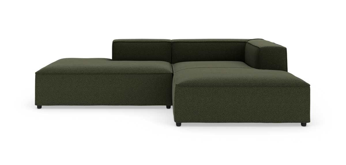 Mørkegrøn modulsofa i L‑form med lav ryg og venstre chaiselong, frilagt på hvid baggrund.