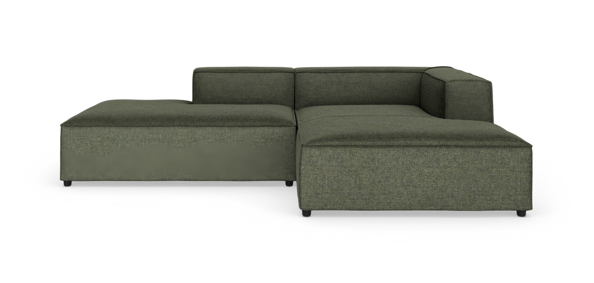 Grøn modulsofa i L-form med lav ryg og brede sæder, fotograferet på hvid studiobaggrund.