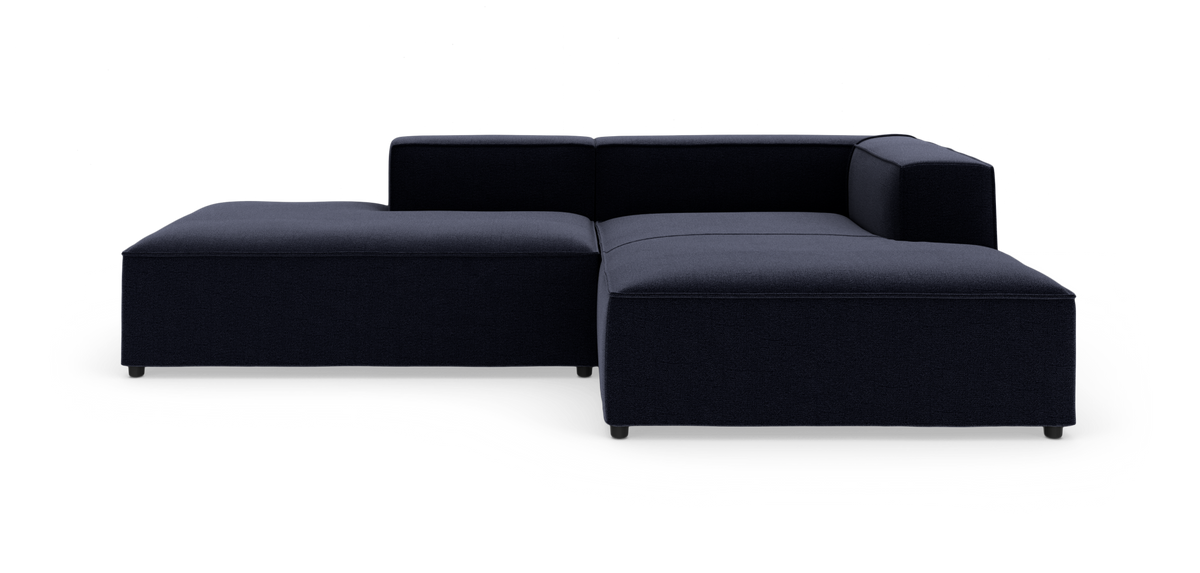 Mørkeblå modulsofa i L-form med lav ryg og højre armlæn, vist i studie på hvid baggrund.