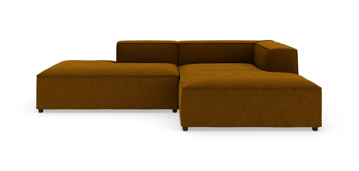 Modulær L‑sofa i sennepsgul/brun tekstil med lav ryg og chaiselong, fritlagt på hvid baggrund.