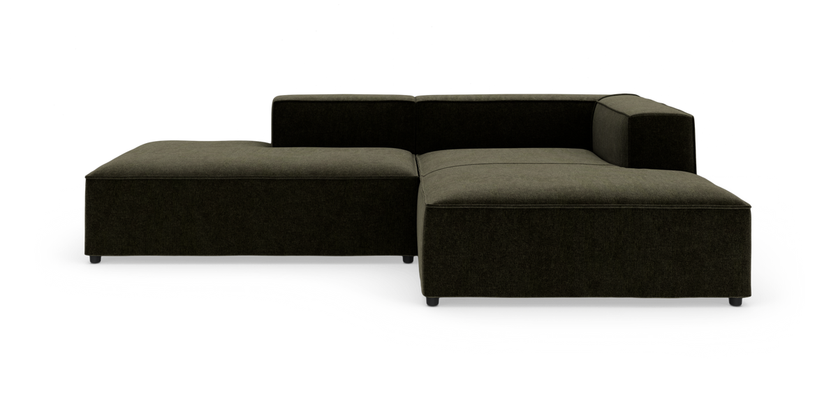 L‑formet modulsofa i mørk olivgrøn stof med lav ryglæn og brede sæder på hvid studiebaggrund.
