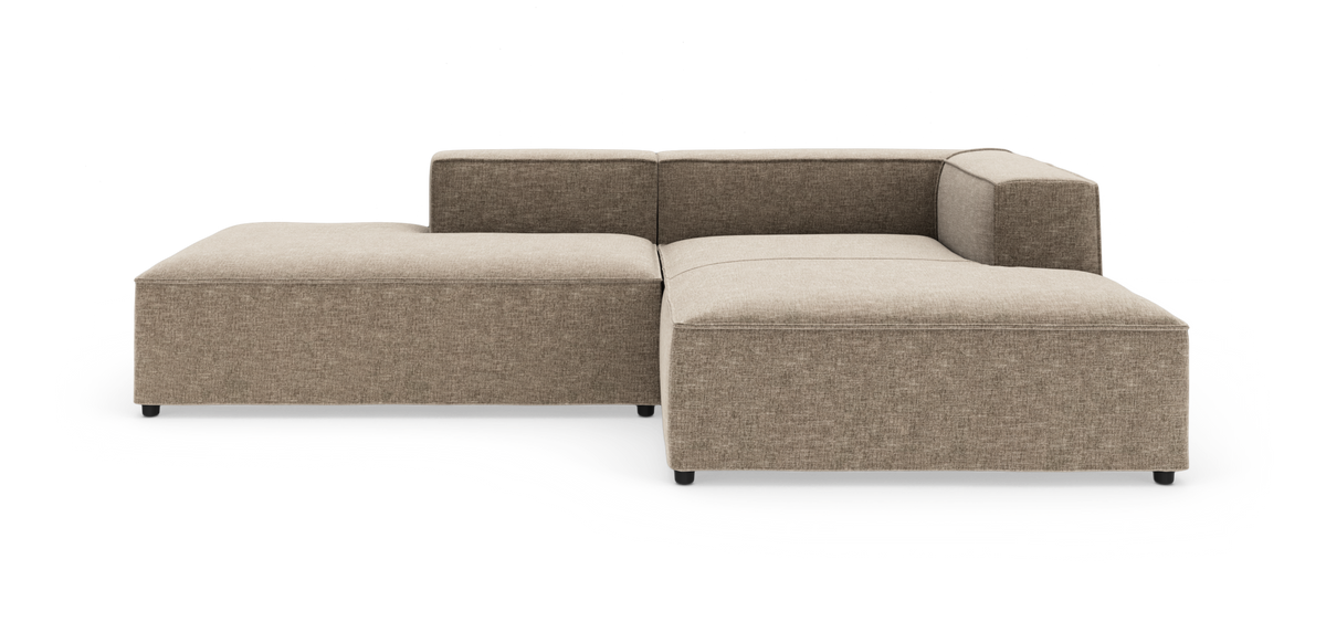 Beige modulsofa i L‑form med lav ryg og venstre chaiselong, frilagt på hvid baggrund.