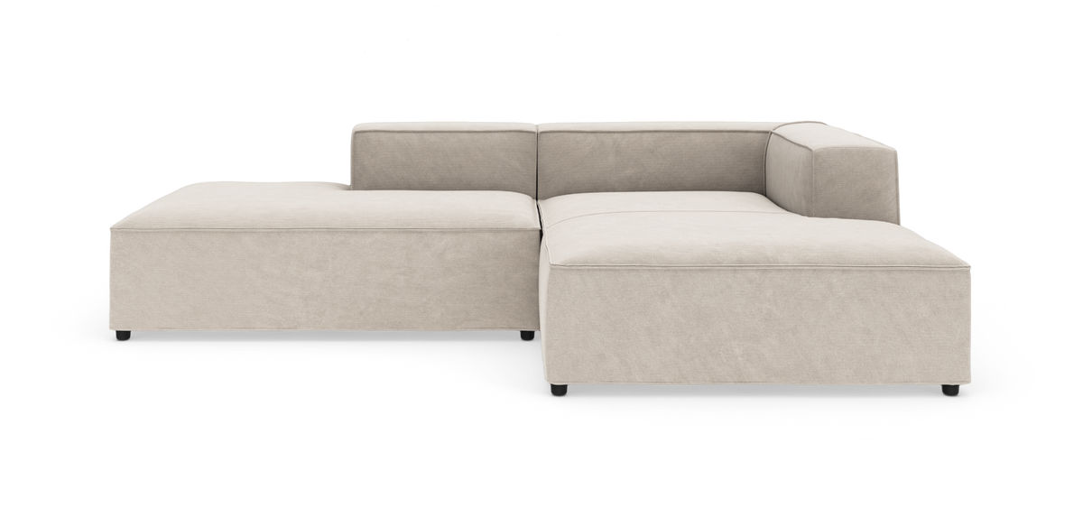 Beige modulsofa i L‑form med lave rygge og brede sædehynder, fritlagt på hvid baggrund.