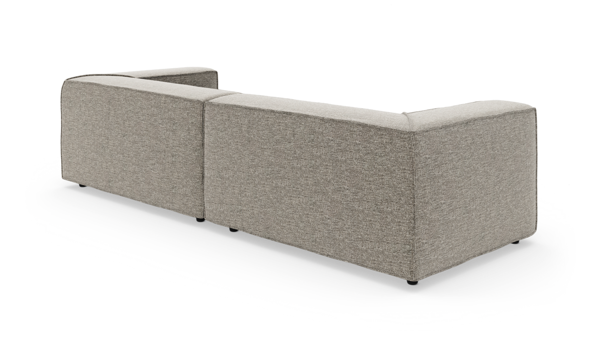 Bagvendt, modulær L‑formet sofa i lysegråt stof, frilagt på hvid baggrund.