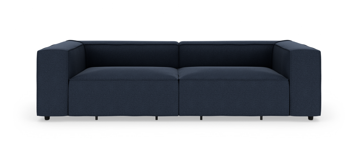 Mørkeblå, moderne modulsofa med brede lave armlæn set lige forfra på hvid baggrund.