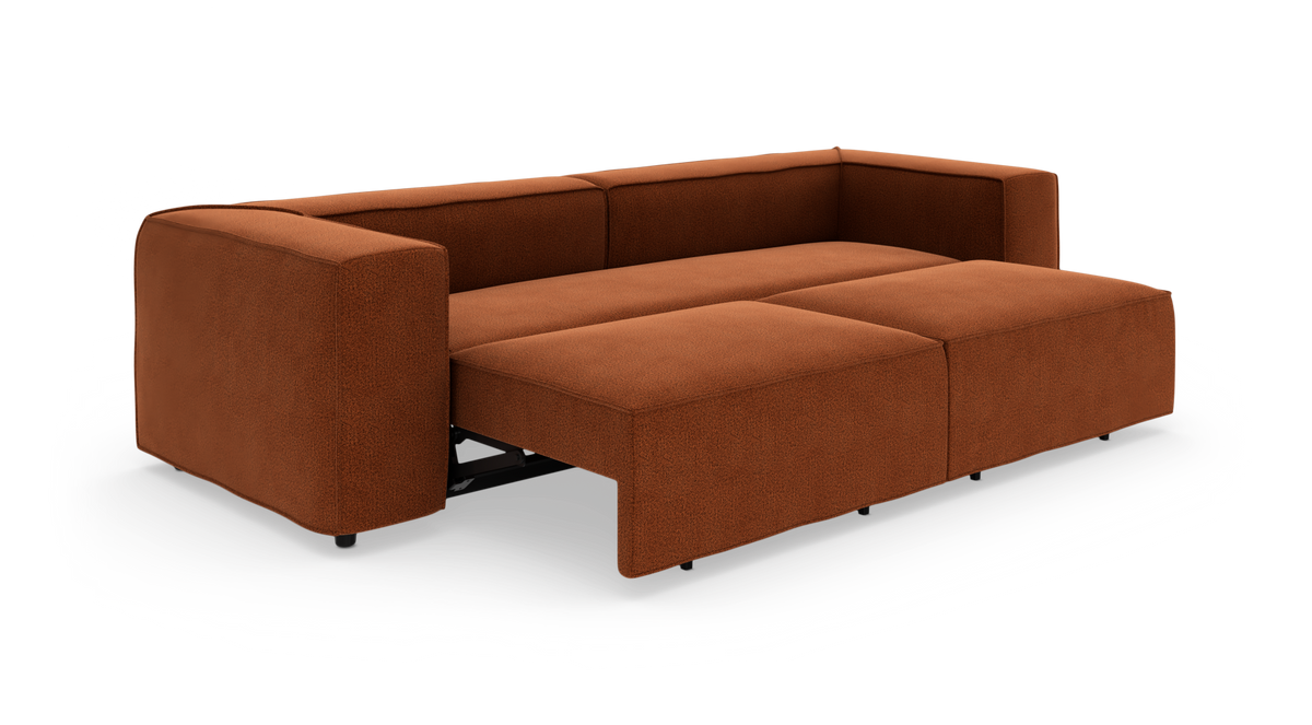 Rustfarvet sovesofa i udslået position, set skråt forfra på hvid baggrund.