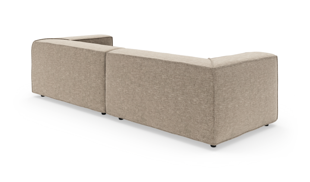 Beige modulsofa med afrundede hjørner set bagfra på hvid baggrund.