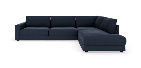 Mørkeblå L‑sofa i stof med bred chaiselong, frontvinkel i studiemiljø.