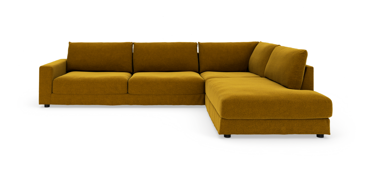 Sennepsgul L-formet hjørnesofa med chaiselong på hvid studio-baggrund, set i skrå frontvinkel.