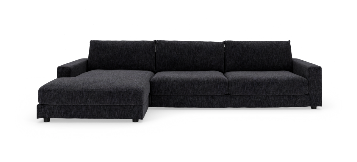 Mørkegrå L‑sofa med venstrevendt chaiselong, tre sæder, brede armlæn og stofbetræk – frontvisning på hvid baggrund.