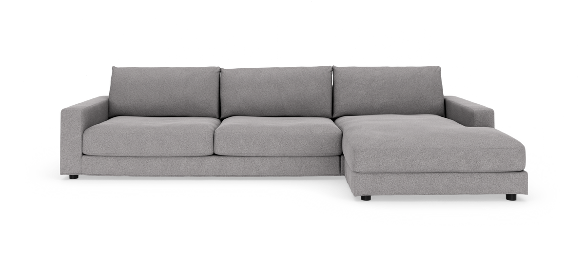 Grå modulsofa med chaiselong til højre, tre sædehynder og brede armlæn på hvid frilagt baggrund.